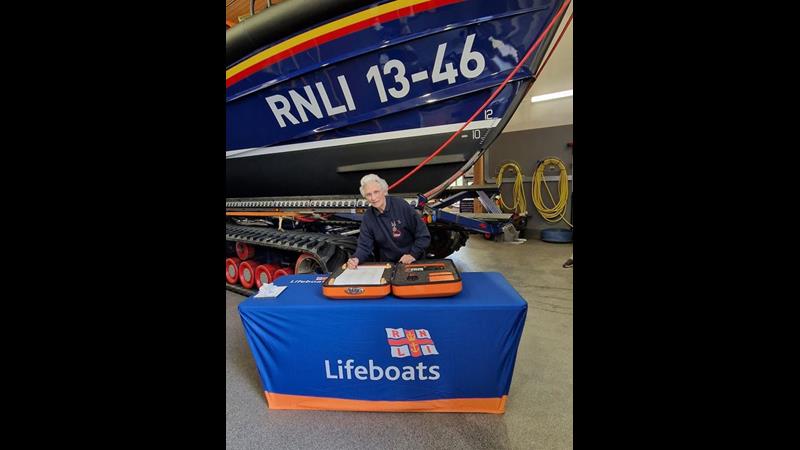 Sheila Warner MBE signing 200th anniversary RNLI scroll in front of Wells RNLI’s Shannon class lifeboat ‘Duke of Edinburgh’