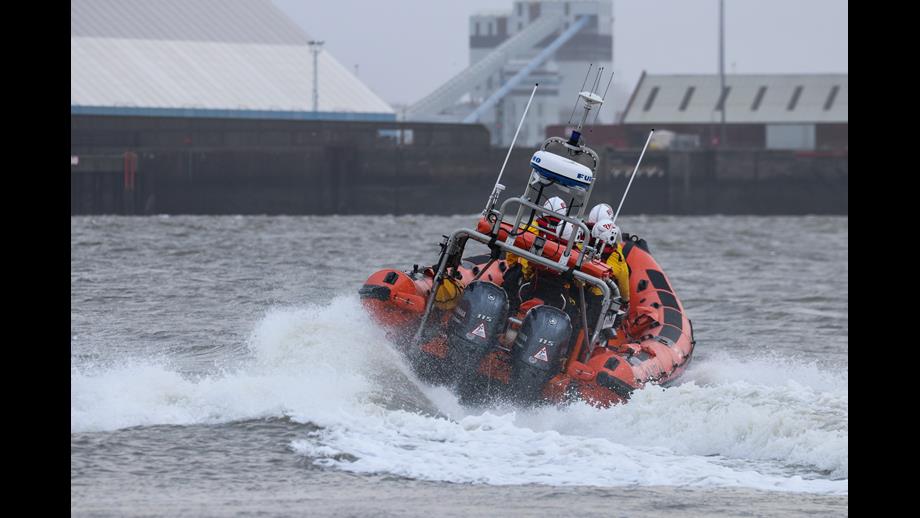 The rear of New Brighton RNLI's Atlantic-85 lifeboat can be seen causing wake on the River Mersey as it heads away from camera, launching.

