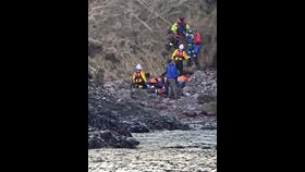 Picture of volunteer lifeboat crew and coastguard rescue teams providing assistance to injured walkers at the bottom of cliffs