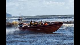 An orange RNLI Atlantic 85 lifeboat and crew at sea.