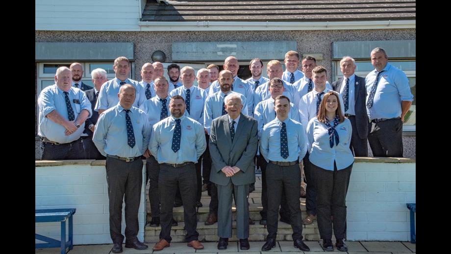 Full crew of Workington RNLI dressed in blue shirts and ties with Bob McLaughlin in middle
