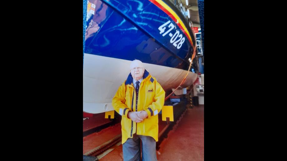 Bob McLaughlin in yellow jacket in front of lifeboat 