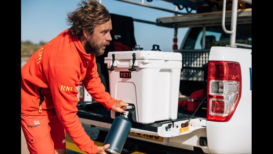 RNLI lifeguard filling their water bottle using a Yeti cooler