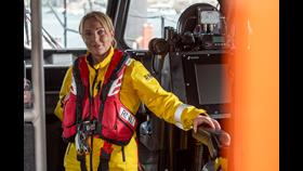 Photo of Susan in yellow RNLI PPE in the wheelhouse of an lifeboat