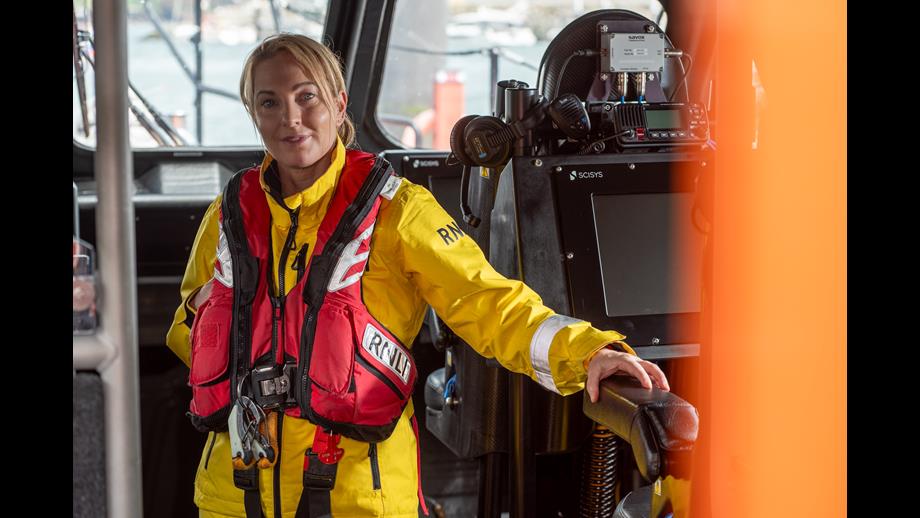 Photo of Susan in yellow RNLI PPE in the wheelhouse of an lifeboat