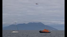 Casualty vessel, lifeboat and Coastguard helicopter on scene with Rum in background