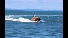lifeboat crashing through waves in front of an offshore windfarm 