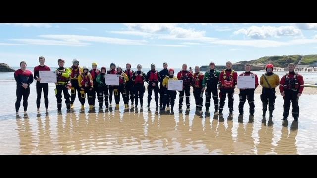 Agencies involved in water safety stand on the beach holding placards with the details of actions they will take to support the campaign
