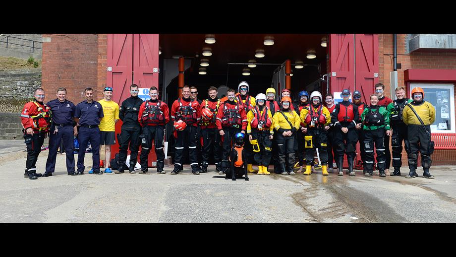 Large group of people lined up, outside the big red doors of the Lifeboat Station