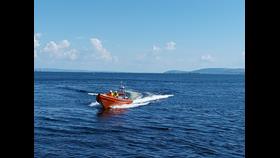 Inshore lifeboat on open water with a wake visible behind on an exercise on Galway Bay. Sunny day with blue skies
