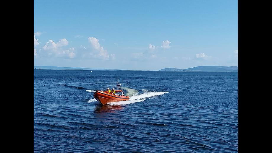 Inshore lifeboat on open water with a wake visible behind on an exercise on Galway Bay. Sunny day with blue skies