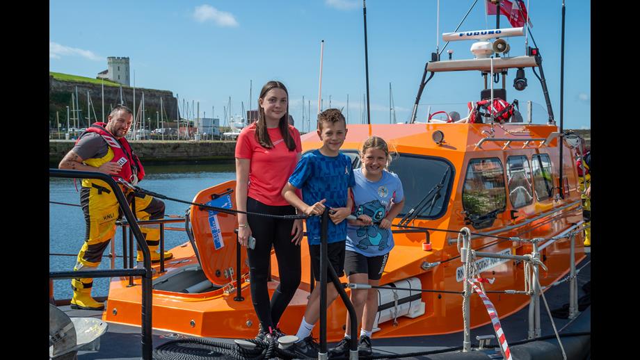 Three children on Shannon lifeboat with crew member behind them 