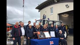 Crew and fundraising volunteers gathered for the signing of the scroll with the station in background