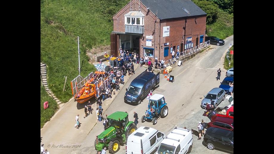 Aerial photo of the slipway and lifeboat station with E-Transit, escorting tractors and Atlantic 85 Lifeboat. A small crowd of people looking on.