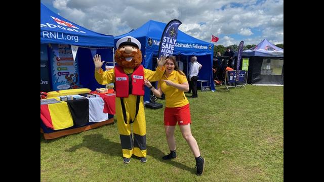 Stormy Stan mascot to the left of a RNLI lifeguard wearing yellow and red