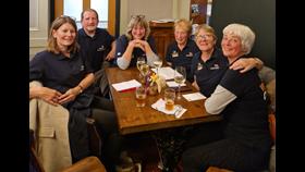 6 people in Wells RNLI polo shirts sitting round a table.