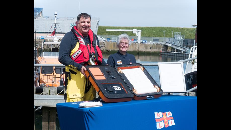 Peter Walker and Margaret Driscoll stand with the RNLI 200th anniversary scroll, the Eyemouth lifeboat in the background