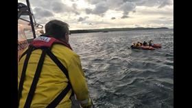 Two divers are helped aboard Eyemouth RNLI inshore lifeboat, watched over by volunteers on the all-weather lifeboat