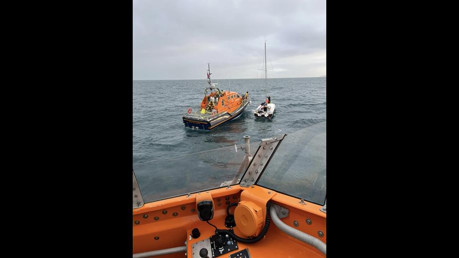 Shows two lifeboats at work on a yacht rescue