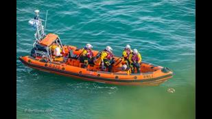View from the clifftop of lifeboat and wreath floating on the water.