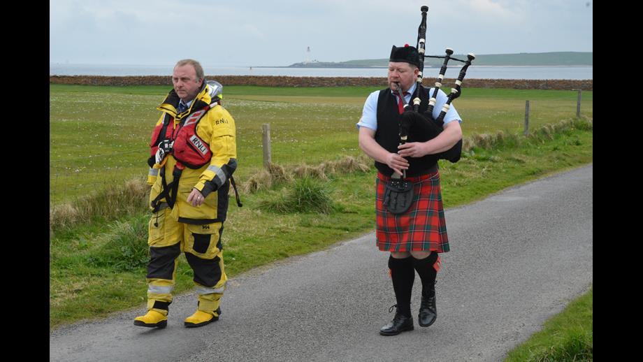 A lone piper (right) with crew man escort (left)