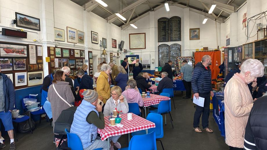 New Brighton RNLI's boathouse is full of people - some browsing craft and cake stalls, others sat enjoying themselves.