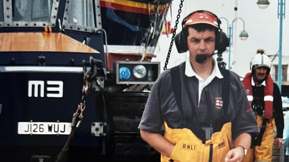 Man standing infront of RNLI tractor with headset on in RNLI clothing