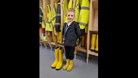 6 year old William Stockley in yellow wellies standing next to a large pair of crew RNLI wellies
