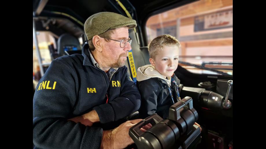 Man and young lad looking at a screen on the lifeboat 