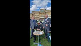 Three men in suits and medals at a table outside Buckingham Palace