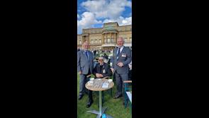 Three men in suits and medals at a table outside Buckingham Palace