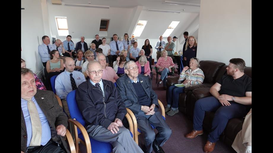 Volunteers sit in rows in smart dress at Cullercoats lifeboat station 