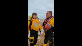 Father and son, Peter and Samuel Leigh in yellow and black RNLI kit share a joke after Sam's first trip in the lifeboat with his dad