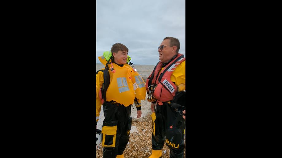 Father and son, Peter and Samuel Leigh in yellow and black RNLI kit share a joke after Sam's first trip in the lifeboat with his dad