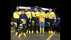Six RNLI crew stand in front of a Land Rover