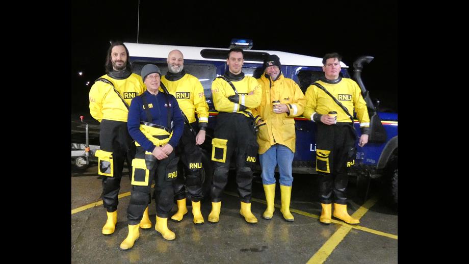 Six RNLI crew stand in front of a Land Rover