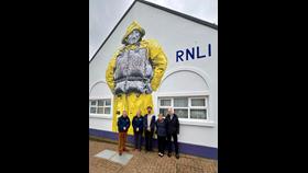 Dedication of the mural at the north gable end of the St Helier lifeboat station. The mural depicts Coxswain Tommy King wearing his 1949 lifeboat oilskins. The artist, Ben Robertson, is standing in front of the mural with the grandson of Tommy King and the RNLI management team.