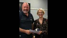 The photo shows Nick and Alison smiling while she presents him with his certificate