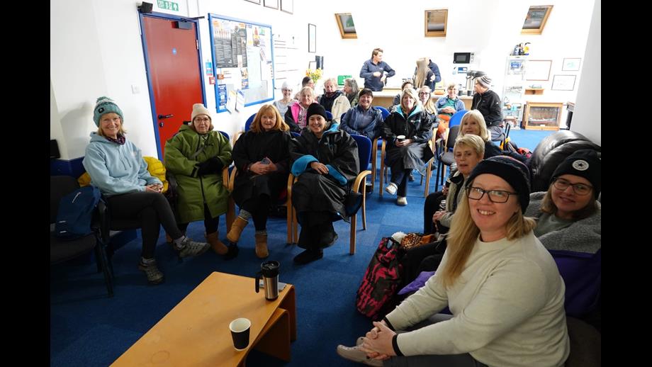 People in outdoor wear gather in front of a presenter at water safety talks