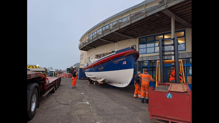 Workers in high vis workwear around RNLI heritage lifeboat in front of museum