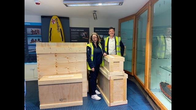 Two people in a Hi Vis vests next to wooden boxes.