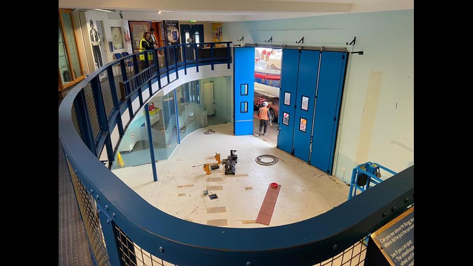 View of an empty museum room from balcony. Fencing of balcony stretches along the left side of the image.