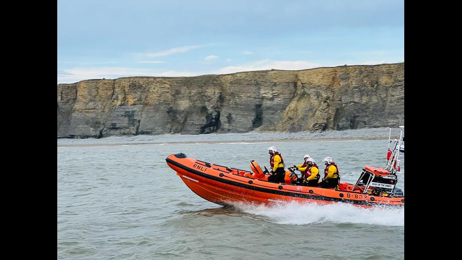 Porthcawl RNLI lifeboat assisting in the rescue with the cliffs around Nash Point in the background