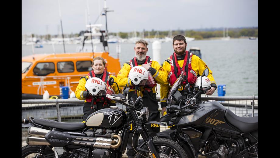 RNLI lifeboat crew standing in front of Daniel Craig's motorbikes