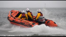 Inshore lifeboat moving through water with three RNLI crew onboard 