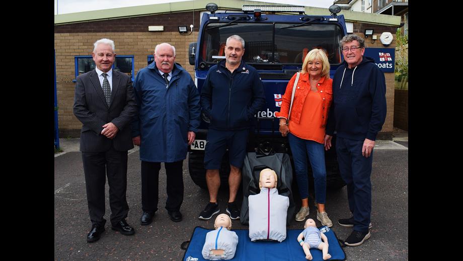 Individuals stood in front of the BV launch vehicle outside the station with the CPR family set in front of them