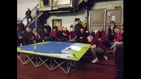 An audience sit round a table diorama of the Irish Sea with models