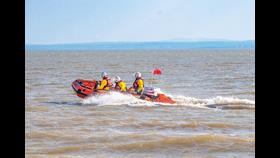 The D class lifeboat can be seen moving across the water with three crew members on board