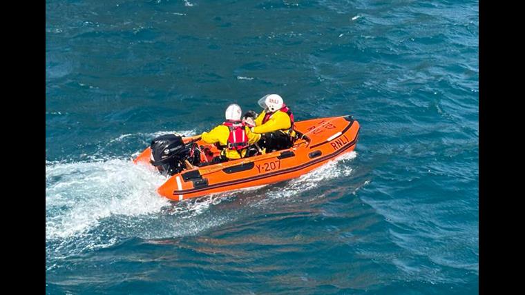 Shows RNLI crewmen rescuing a dog