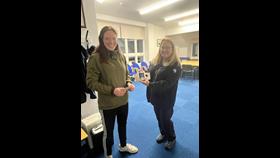 Two women, one handing over a pager to the other inside a lifeboat station